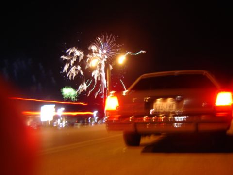1988 Ford LTD Crown Victoria - A sedan drives past fireworks at night, its taillights glowing.