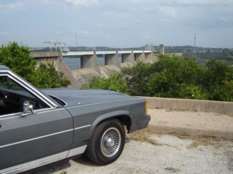 1988 Ford LTD Crown Victoria - A gray 1988 Ford Crown Victoria LTD is parked with a scenic view of a dam and surrounding landscape.