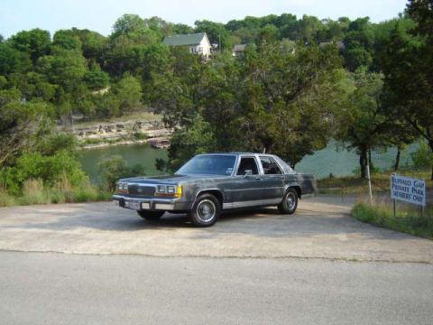 1988 Ford LTD Crown Victoria - A 1980s Ford sedan is parked near a lake, with a sign indicating a private park.