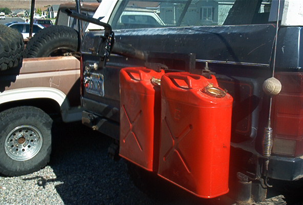 1986 Ford Bronco rear with two red jerry cans mounted on the side and a spare tire in the bed