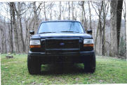 1992 Ford Bronco - Front view of a black 1992 Ford Bronco parked outdoors on a grassy area with trees.