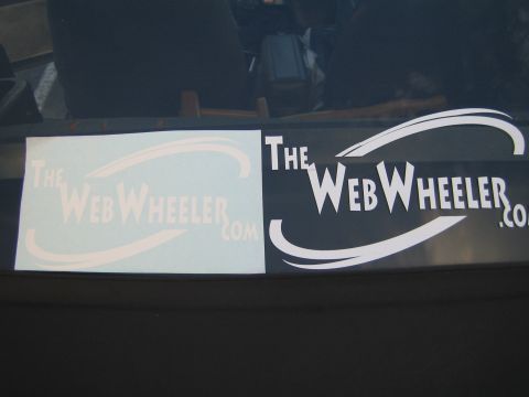 1990 Ford Bronco - Two vinyl decals reading TheWebWheeler.com, one solid white and one printed, displayed on a dark vehicle window.