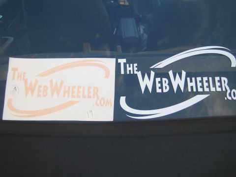 1990 Ford Bronco - orange paper decal and a white 'TheWebWheeler.com' window sticker shown on a car's rear glass.