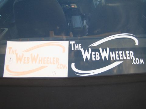 1990 Ford Bronco - Orange and white 'TheWebWheeler.com' logo decals displayed against a vehicle's rear window.