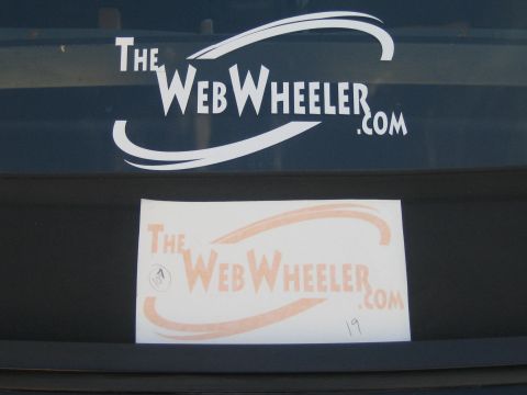 1990 Ford Bronco - White and orange 'TheWebWheeler.com' logo decals positioned on a dark vehicle's rear area.