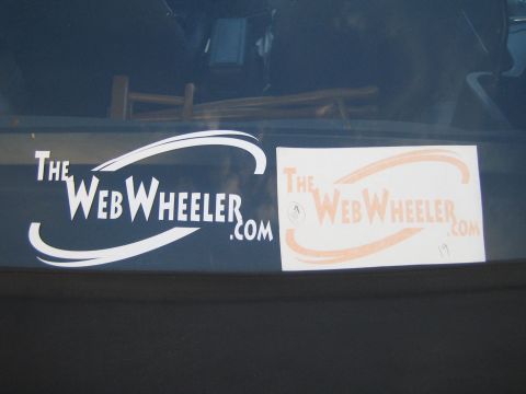 1990 Ford Bronco - white window decal beside an orange logo print, both reading 'TheWebWheeler.com', on a vehicle.