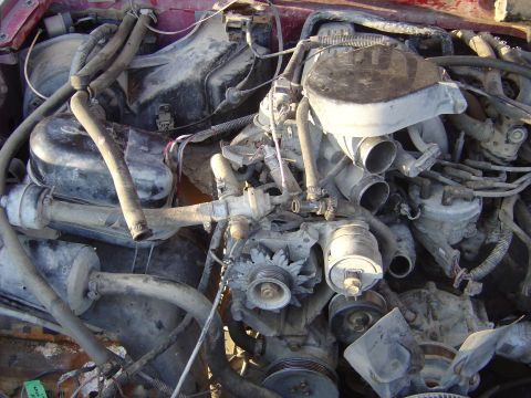 1986 Ford F-150 - Close-up view of a cluttered engine bay with various parts and hoses.