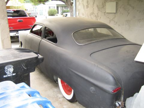 1968 Ford Mustang - This matte black coupe, likely from the early 1950s, sits in a garage next to a red pickup truck.