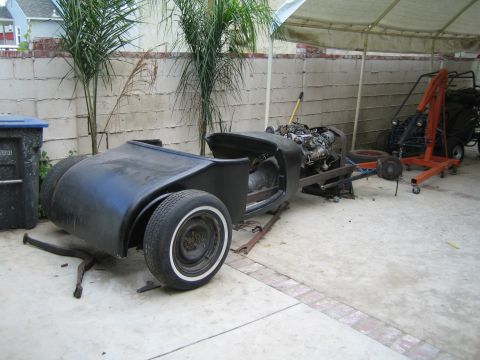 1968 Ford Mustang - Project car chassis with engine and rear fenders, undergoing restoration outdoors.