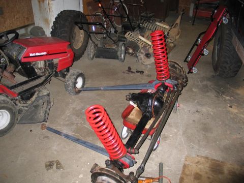 1995 Ford Bronco - A red tractor and other items are in a garage with a disassembled front axle assembly.