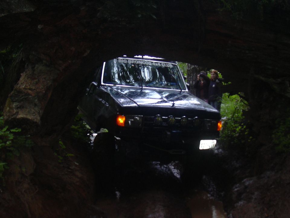 1991 Ford Bronco driving through a muddy, wooded trail