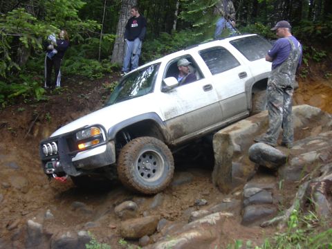 1991 Ford Bronco - A white SUV attempts to traverse a challenging rocky terrain during an off-road event.
