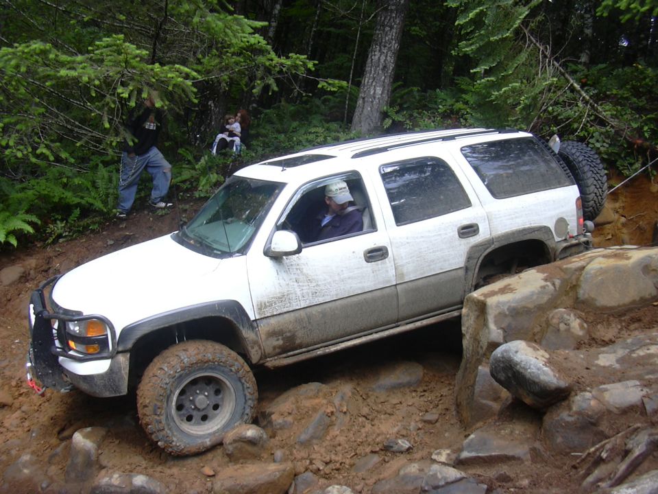 White SUV off-roading on a muddy, rocky path