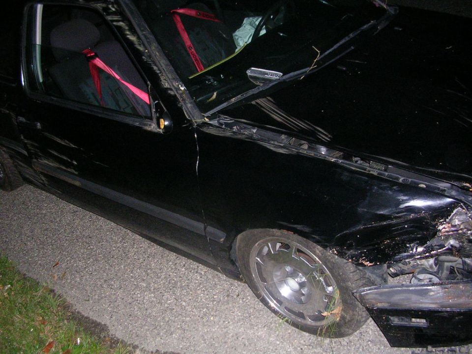 Black coupe with severe side and front collision damage at night