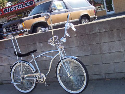 1995 Ford Bronco - A custom bicycle and a pickup truck are parked on a street in front of a bicycle shop.