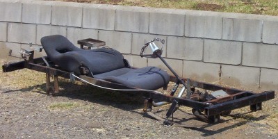 1995 Ford Bronco - A go-kart chassis with a racing seat and steering wheel is parked outdoors.