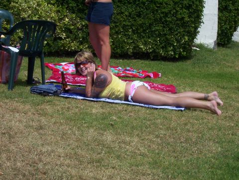 1995 Ford Bronco - A woman relaxes on the grass on a sunny day, holding a beer bottle and smiling at a picnic blanket.