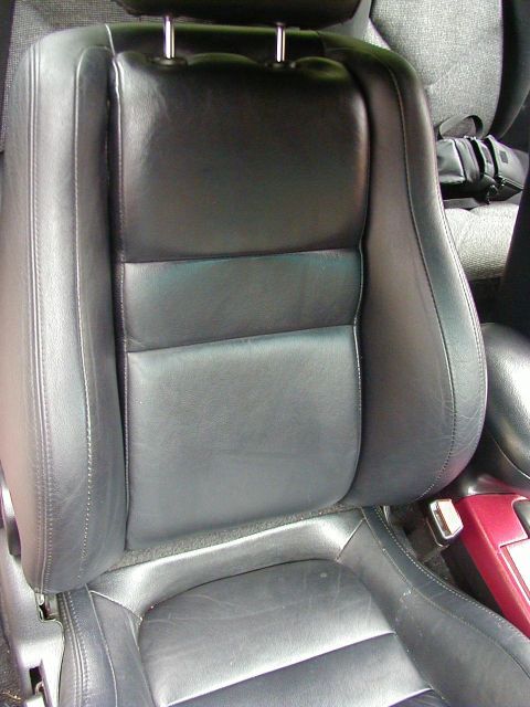 1994 Ford Probe - Close-up view of a car's black leather interior seat, showing stitching detail and a hint of red trim.
