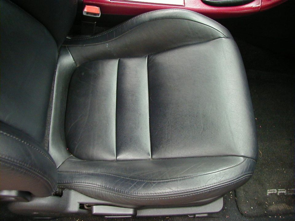Black leather car seat with visible stitching and wear, interior view