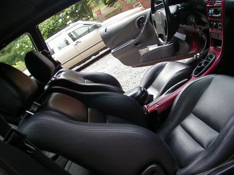 1994 Ford Probe - The interior of a 1994 Ford Probe features black leather bucket seats and red trim accents on the dashboard and center console.