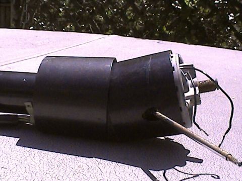 1978 Ford Bronco - This black steering column part, likely from a vehicle's interior, is shown outdoors with visible wiring and a metal rod extending from it.