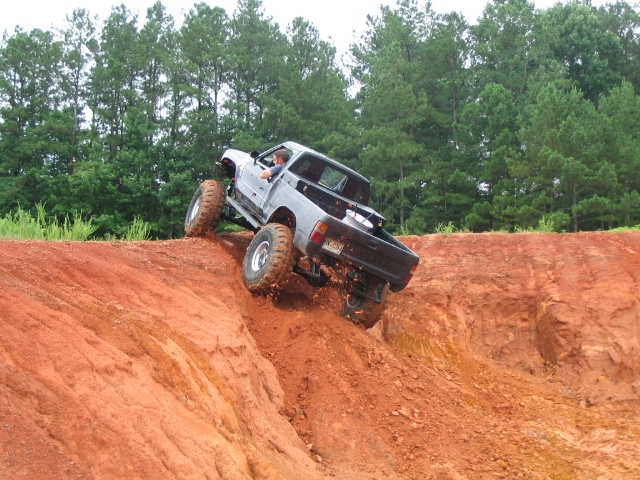 Pickup truck with large tires climbing a steep dirt embankment