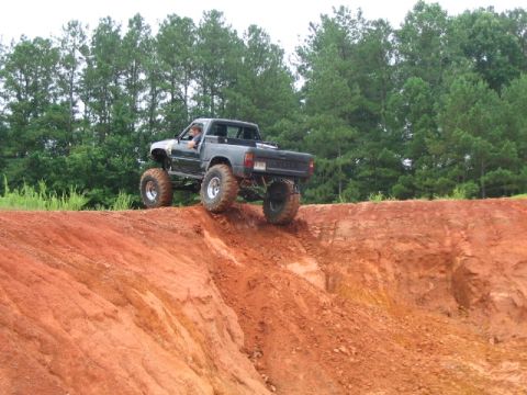 1986 Ford F-150 - A modified pickup truck navigates a steep dirt incline, its off-road capabilities.