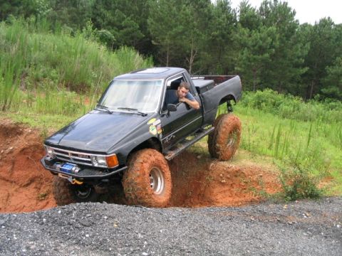 1986 Ford F-150 - Modified Toyota pickup truck tackling rough terrain off-road.