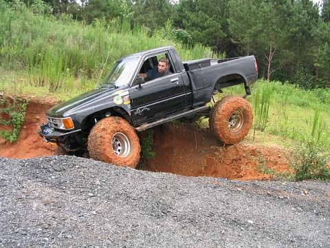 1986 Ford F-150 - A man drives a modified pickup truck through a challenging off-road course.