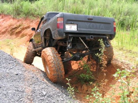 1986 Ford F-150 - Toyota pickup truck with large tires navigating an off-road trail.
