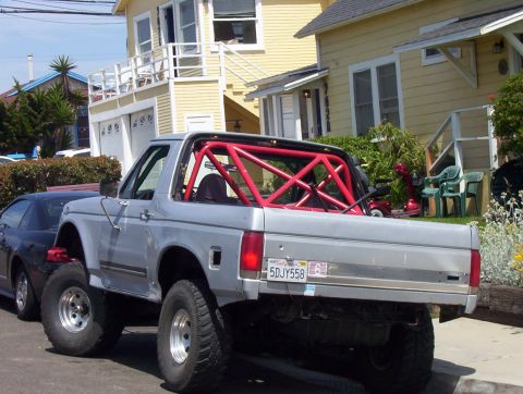 1995 Ford Bronco - This lifted Ford Bronco, modified with a red roll cage, is parked on a residential street.