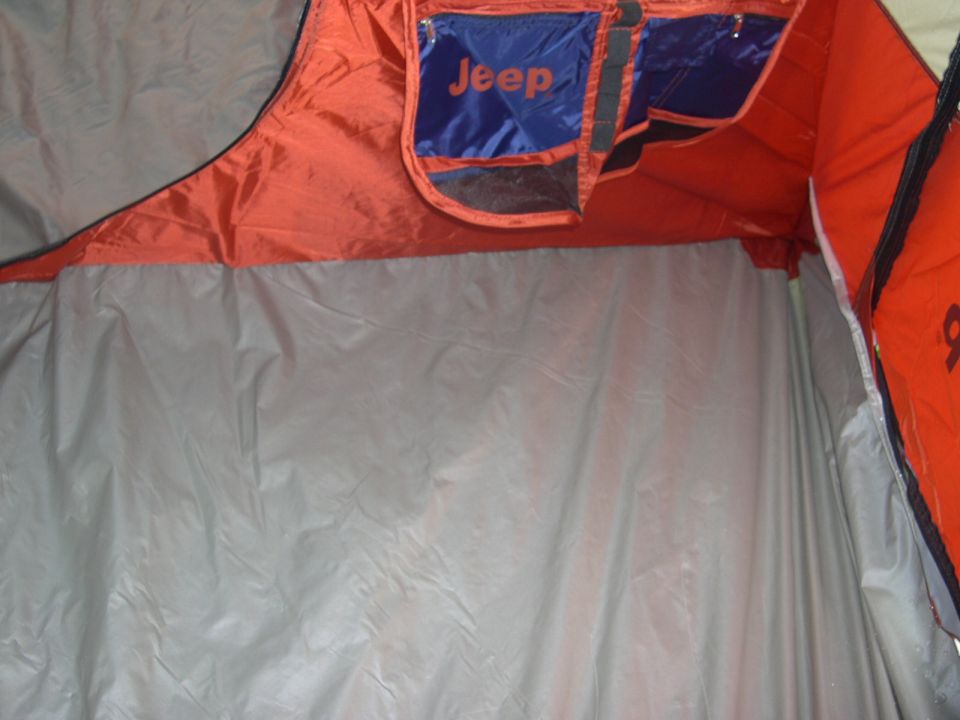 Interior of a tent showing orange fabric and gray walls, with blue pockets labeled "Jeep"