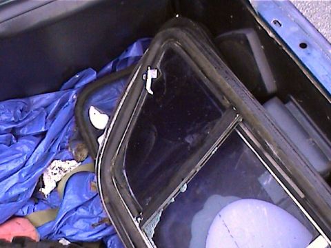 1978 Ford Bronco - Car window parts are stored in the cargo area, covered by a blue tarp.