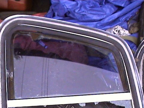 1978 Ford Bronco - Close-up of a vehicle's window trim and glass, reflecting a purple interior.