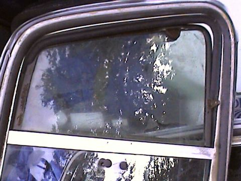 1978 Ford Bronco - Close-up of a vehicle's window frame and glass, with visible water spots and reflections.