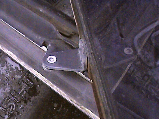 Close-up of a black metal door hinge bracket attached to a metal frame