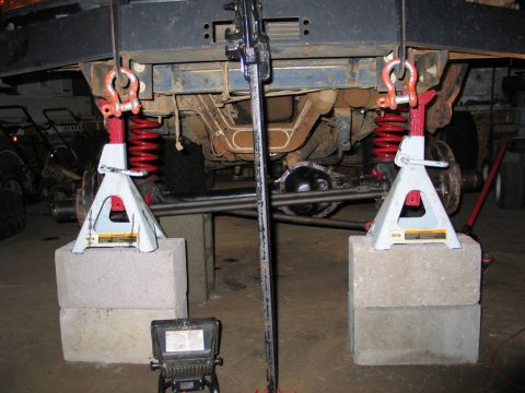 1995 Ford Bronco - Undercarriage of a vehicle being worked on, supported by jack stands and concrete blocks.