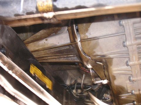 1989 Ford Bronco - Underside view of a vehicle's transmission and associated components, with a visible warning label.