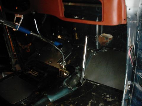 1978 Ford Bronco - The interior of a vehicle shows a floor shifter and exposed metal components, with orange trim on the dashboard.