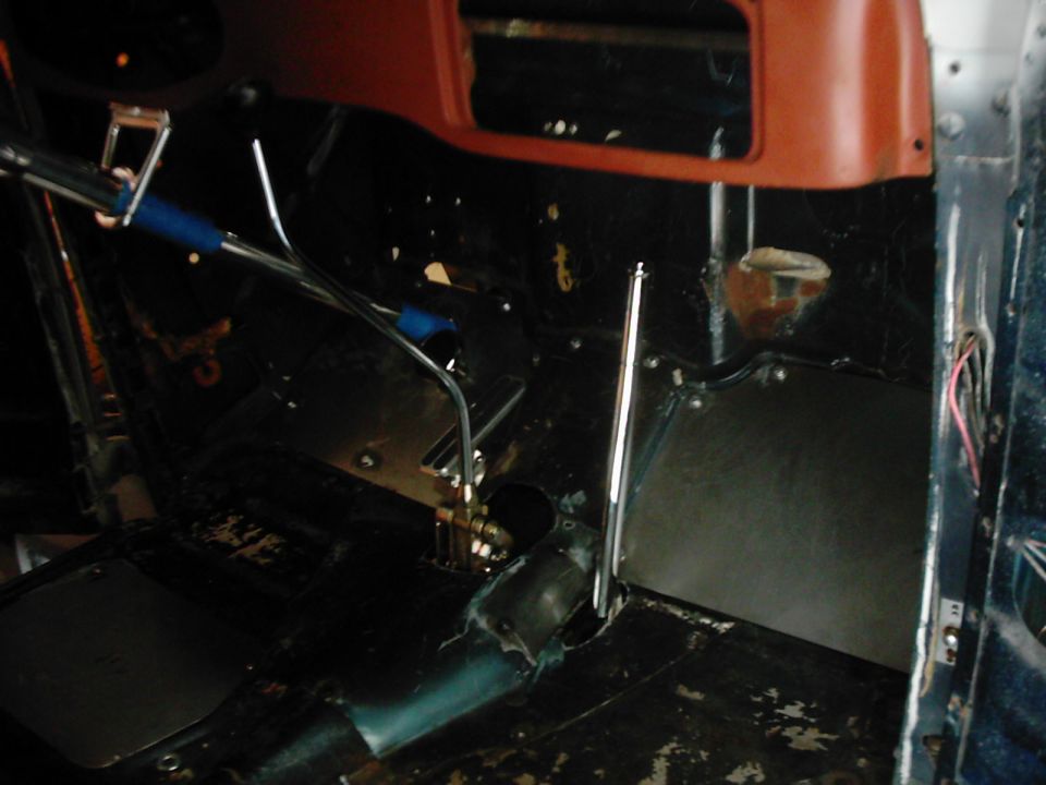 Interior of a vehicle with exposed metal, floor shifter, and orange dashboard trim