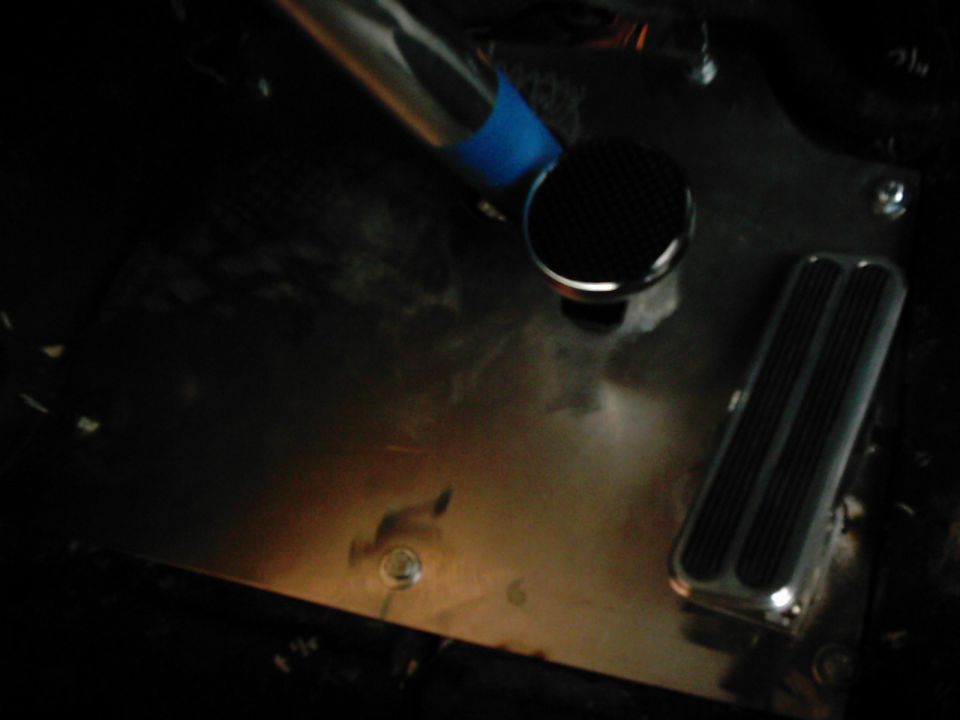Interior floor of a vehicle showing a brake pedal and a floor-mounted shifter knob