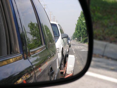 1993 Ford Taurus - Car being towed on a flatbed tow truck, seen from the perspective of the tow truck's side mirror.