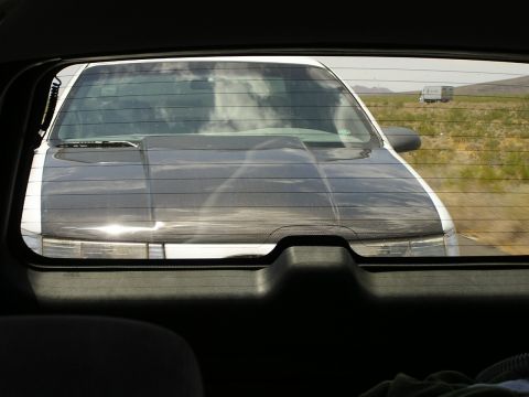 1993 Ford Taurus - Rear view of a 1993 Ford Taurus, distinguished by its aftermarket black hood, driving on a highway.