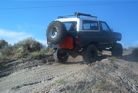 1986 Ford Bronco - This lifted 1980s Ford Bronco navigates an off-road trail under a clear blue sky.
