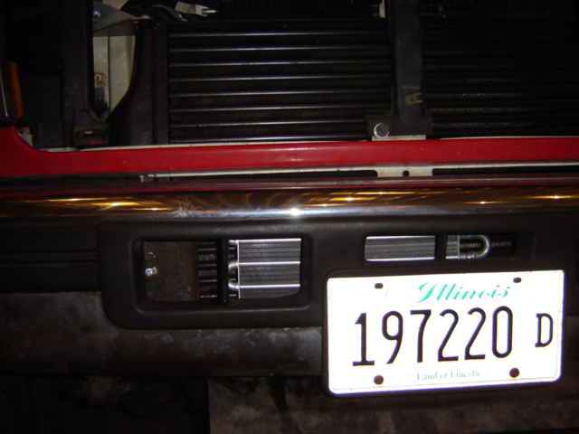 Illinois license plate 197220 D mounted on a vehicle's front bumper, with part of a radiator visible behind it
