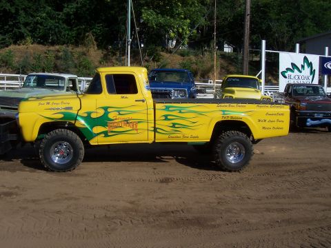 1994 Ford F-150 - This yellow 1956 Ford F-100 pickup truck features custom flame graphics and various sponsor text on its side.