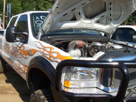 1994 Ford F-150 - This truck has flame graphics and the hood is open, revealing the engine compartment and some aftermarket parts.