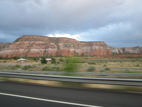 1993 Ford Taurus - A scenic view of layered red rock formations seen from a highway, with a cloudy sky overhead.