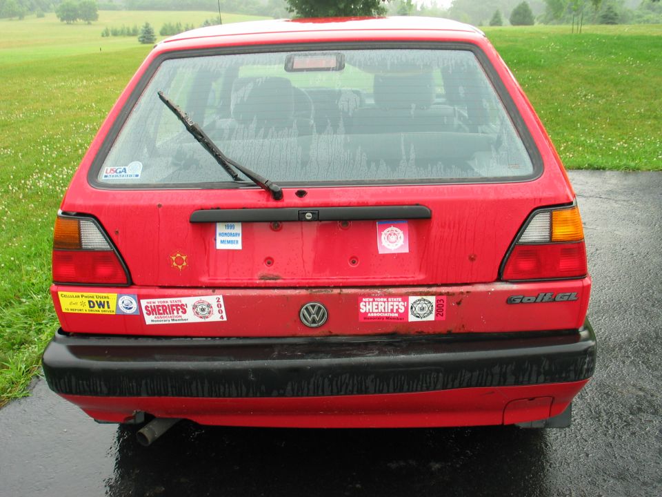 Red Volkswagen Golf GL hatchback with various stickers on the rear, including 'SHERIFFS' and 'DWI'