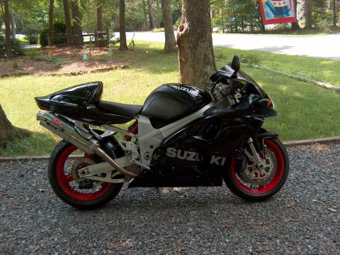 2002 Suzuki TL1000R - Side view of a black 2002 Suzuki TL1000R motorcycle red wheels and an aftermarket exhaust.